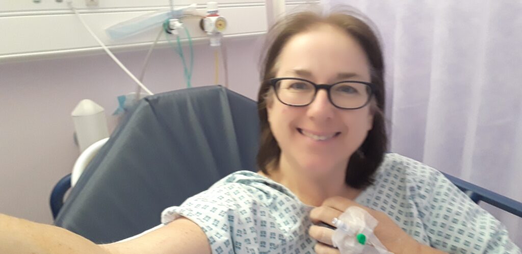 Liz taking a selfie in hospital in a hospital gown