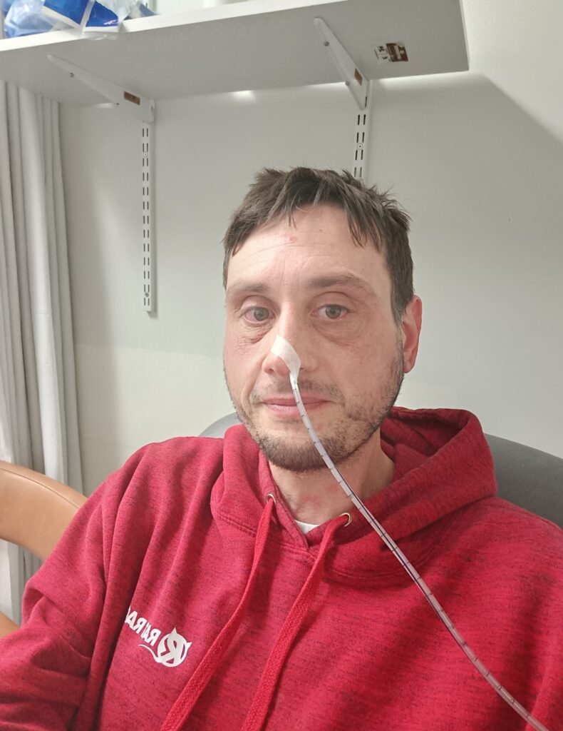 Ian in hospital with a tube coming out of his nose